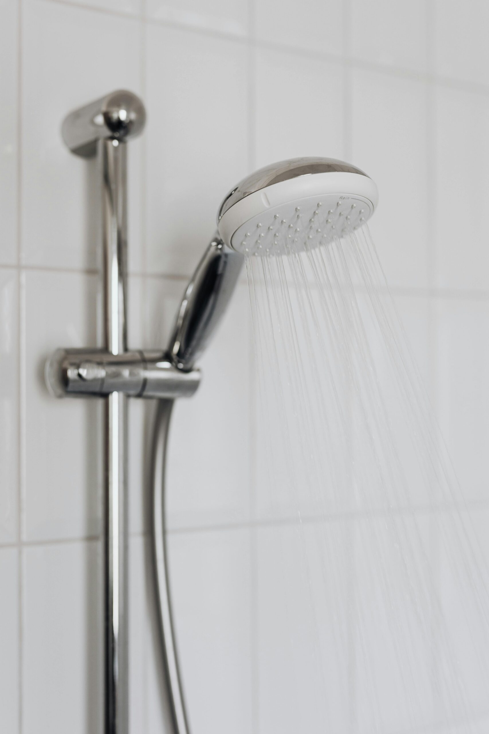 Close-up of a chrome shower head with water flowing, showcasing sleek modern bathroom design.